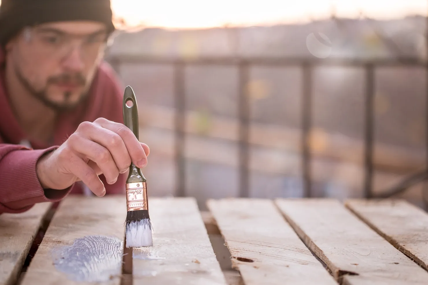 man-paints-with-white-paint-wood